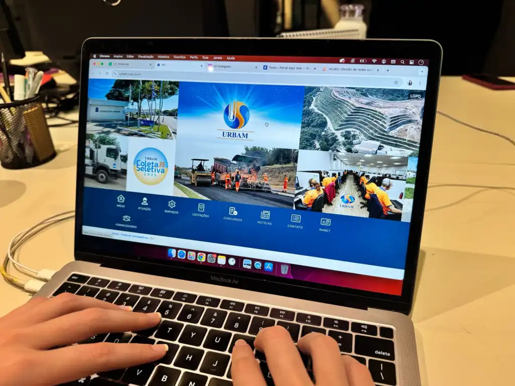 Mãos de uma pessoa no teclado do notebook navegando no site da Urbam de SJC