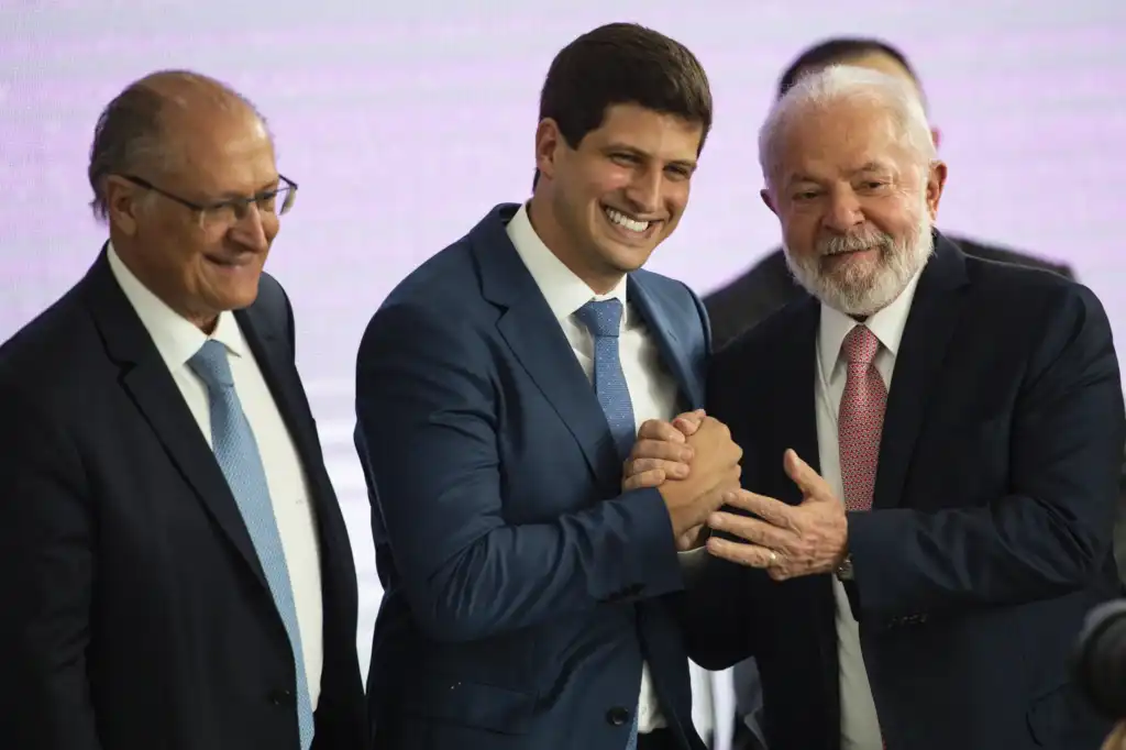 Lula e João Campos dando as mãos para uma foto. Alckmin está do lado