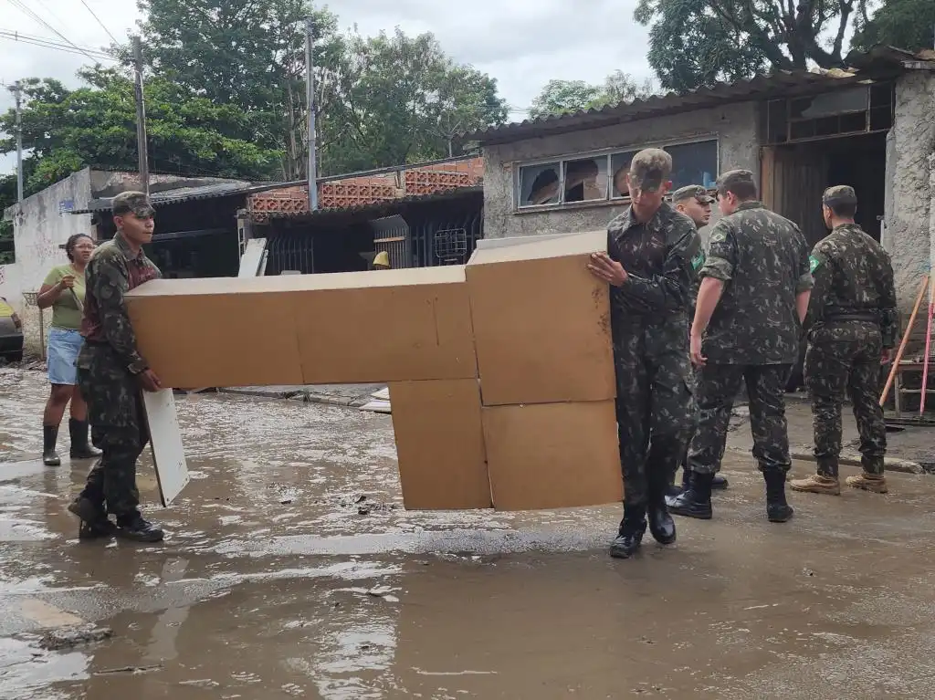 soldados do exército carregando um móvel da casa alagada de um morador de taubaté